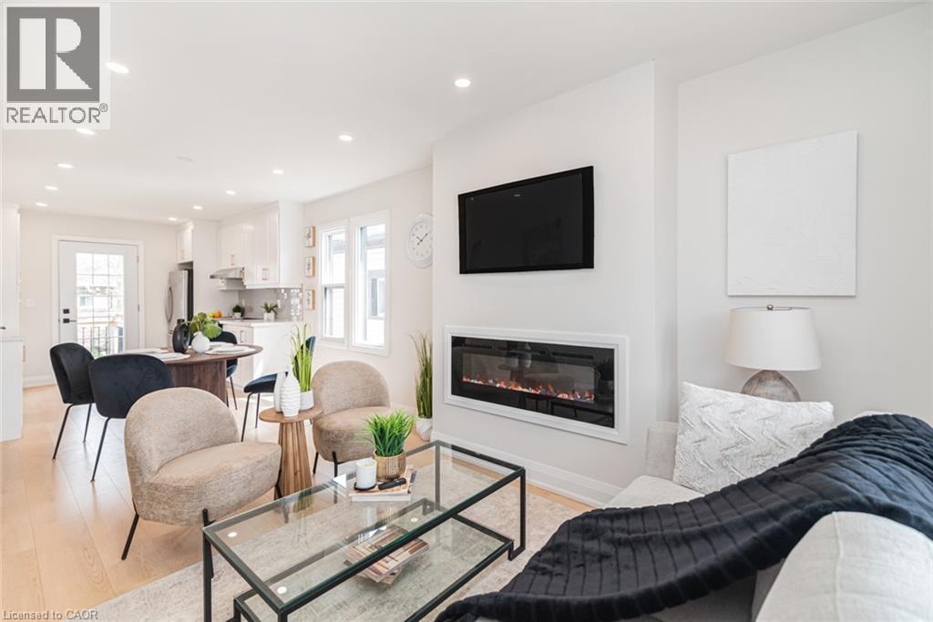 Open-concept living area featuring a built-in linear electric fireplace, recessed lighting, and wood-finish flooring - 297 Britannia Avenue, Hamilton, ON