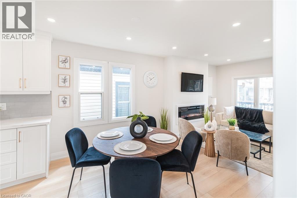 Open concept living space featuring light wood-finish flooring, recessed lighting, a built-in fireplace, and white cabinetry with gold-tone hardware - 297 Britannia Avenue, Hamilton, ON