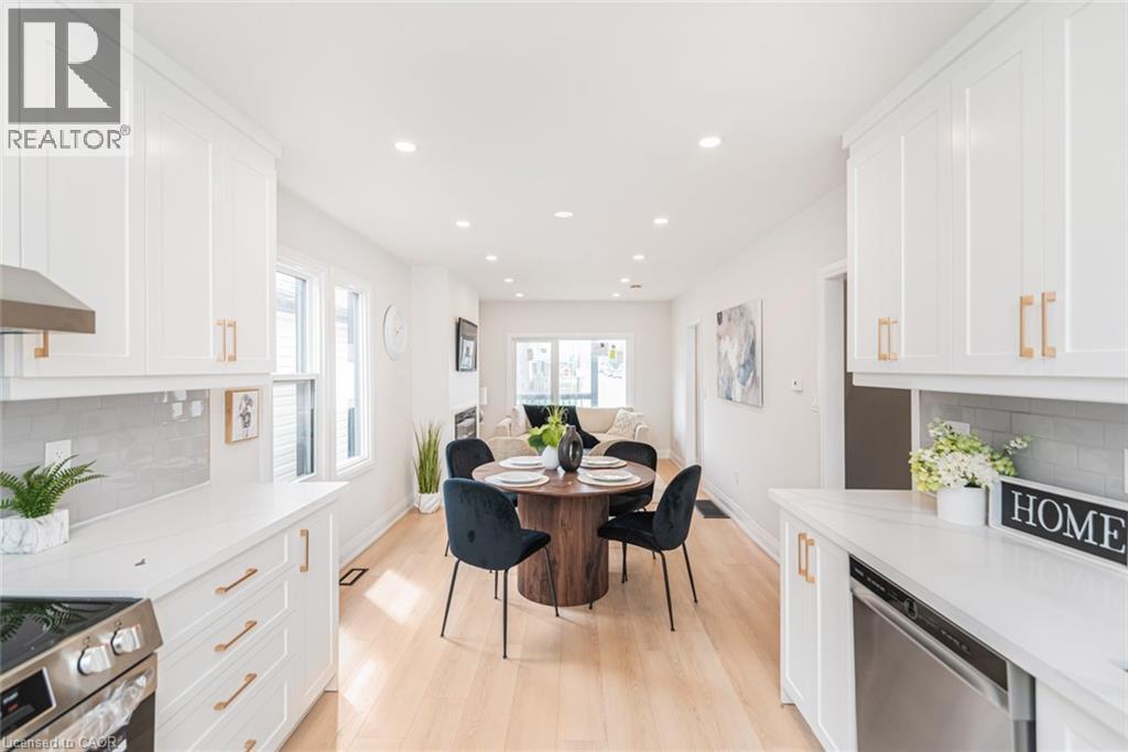 Bright, open-concept kitchen featuring white shaker cabinetry, light-toned wood-finish flooring, recessed lighting, stainless steel appliances, and quartz countertops with a subway tile backsplash - 297 Britannia Avenue, Hamilton, ON