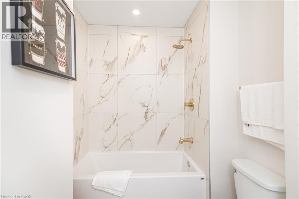 Bathtub with a white surround and polished brass fixtures - 297 Britannia Avenue, Hamilton, ON