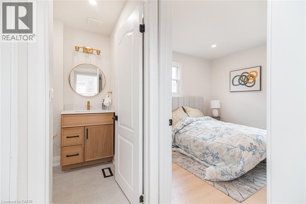 Modern vanity featuring a wood-finish cabinet, white countertop, and gold-finish faucet - 297 Britannia Avenue, Hamilton, ON