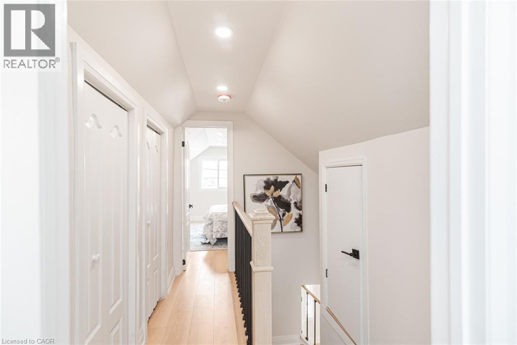 Upper-level hallway featuring light wood-finish flooring, white paneled doors, recessed lighting, and sloped ceilings - 297 Britannia Avenue, Hamilton, ON