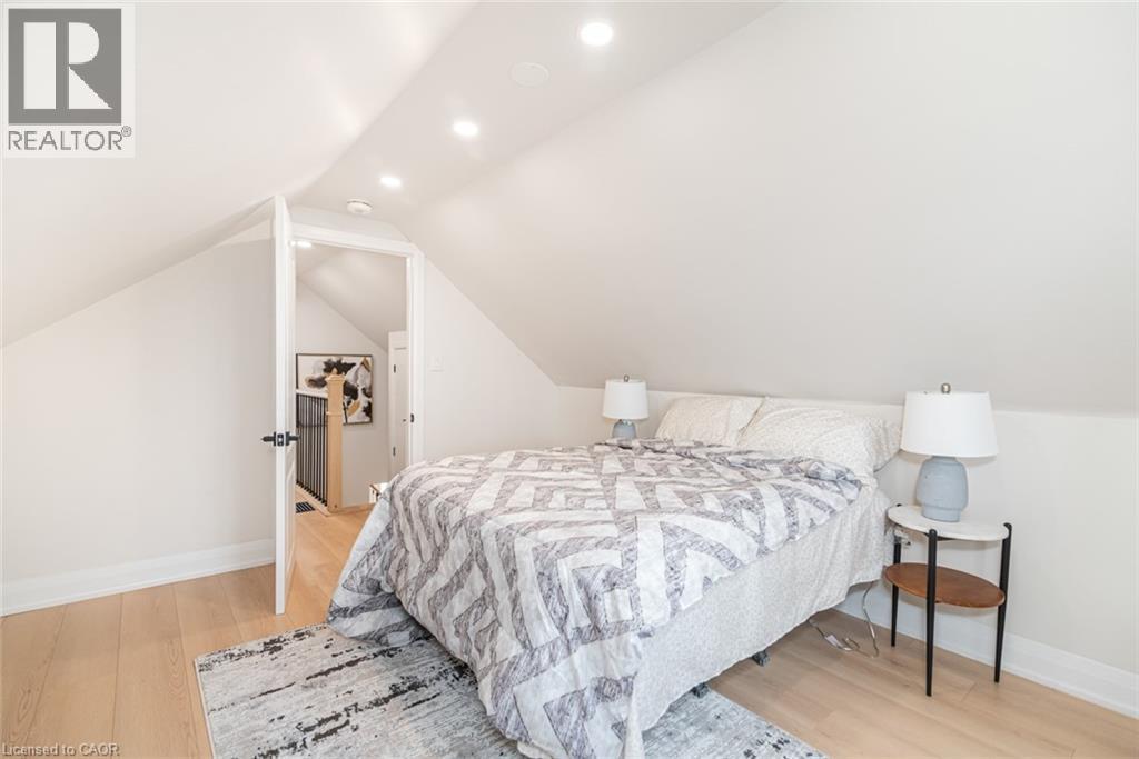 Sloped ceilings with recessed lighting define this room, featuring light wood-finish flooring - 297 Britannia Avenue, Hamilton, ON