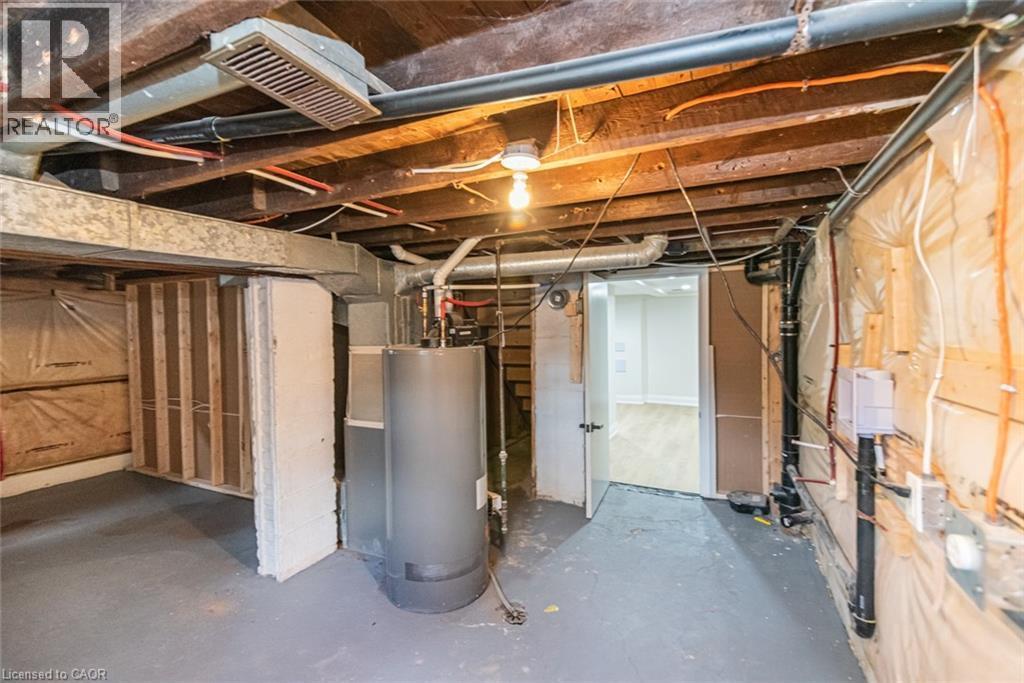 Unfinished basement space featuring exposed wooden ceiling joists, visible HVAC ductwork, and utility piping - 297 Britannia Avenue, Hamilton, ON