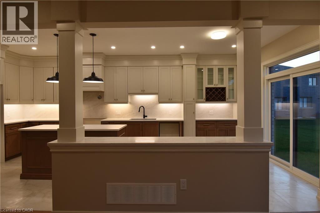 Sophisticated kitchen featuring a two-tiered island with waterfall countertop edge, pendant lighting, and stainless steel sink - 8 Dunlop Road, Hamilton, ON - Indoor Photo Showing Kitchen With Upgraded Kitchen