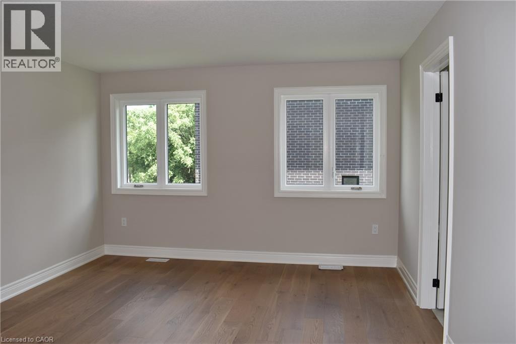 Bright and spacious room featuring hardwood flooring, fresh neutral walls, and abundant natural light from dual windows - 8 Dunlop Road, Hamilton, ON - Indoor Photo Showing Other Room