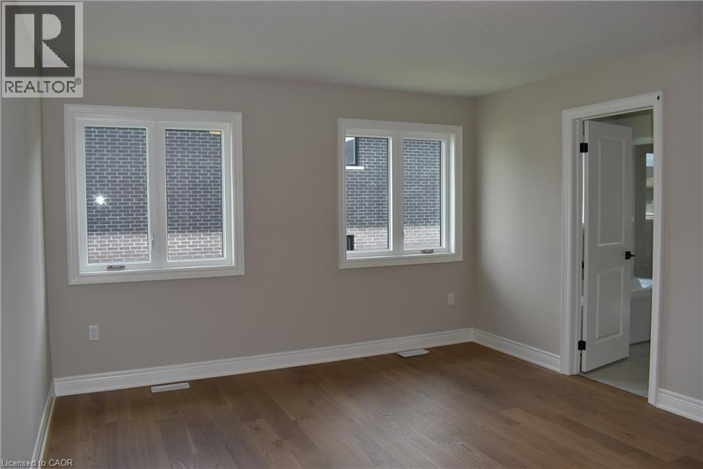 Room featuring wood-finish flooring, two windows with white trim, light gray painted walls, and white baseboards - 8 Dunlop Road, Hamilton, ON - Indoor Photo Showing Other Room