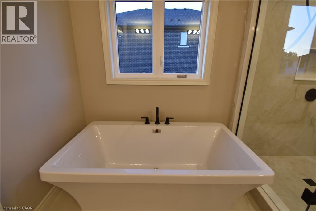 Spa-inspired soaking tub featuring clean lines, a rectangular basin with generous depth, and a contemporary matte black faucet - 8 Dunlop Road, Hamilton, ON - Indoor Photo Showing Bathroom