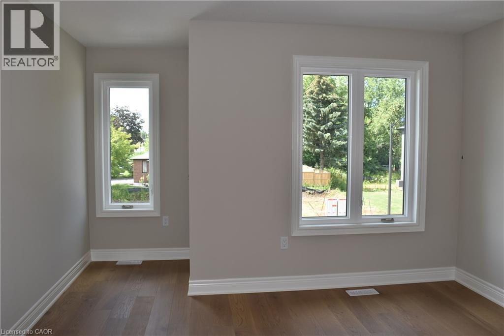 Interior room featuring wood-finish flooring, light-colored walls, white baseboards, and two distinct windows - 8 Dunlop Road, Hamilton, ON - Indoor Photo Showing Other Room
