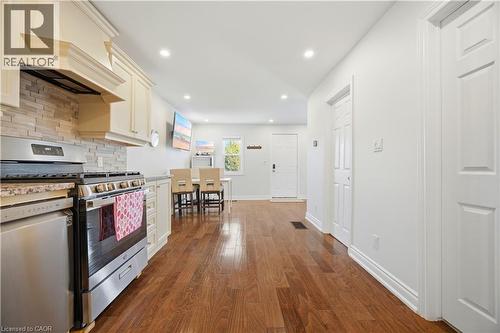 Modern kitchen featuring stainless steel appliances, light-toned cabinetry, a stone backsplash, and granite-style countertops - 71 Beland Avenue N, Hamilton, ON 