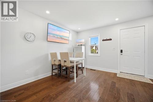 Bright interior space featuring rich wood-finish flooring, recessed lighting, and a white paneled entry door - 71 Beland Avenue N, Hamilton, ON 