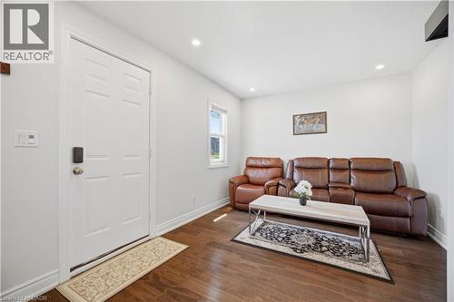 Bright entry area featuring wood-finish flooring, recessed lighting, and a multi-panel door with smart lock hardware - 71 Beland Avenue N, Hamilton, ON 