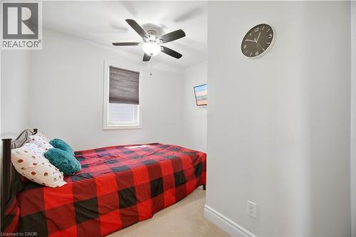 Bedroom featuring a ceiling fan with integrated lighting, a window with a roller shade, light-toned carpeting, and neutral wall tones - 71 Beland Avenue N, Hamilton, ON 