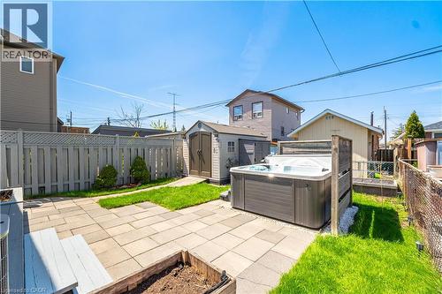 Outdoor spa area featuring a paver patio, a freestanding shed, and a privacy fence - 71 Beland Avenue N, Hamilton, ON 
