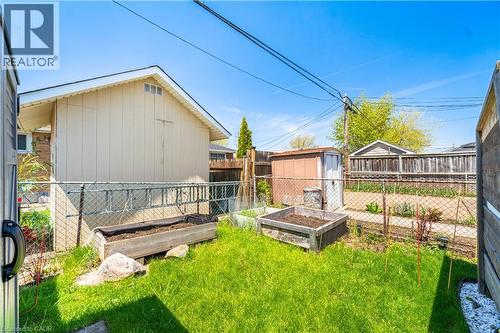 Fenced backyard with established lawn, two raised garden beds, and a storage shed - 71 Beland Avenue N, Hamilton, ON 