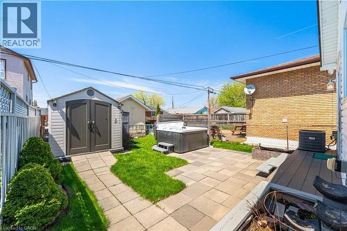 Backyard featuring a paver patio with a hot tub, a built-in storage shed, and a composite deck platform - 71 Beland Avenue N, Hamilton, ON 