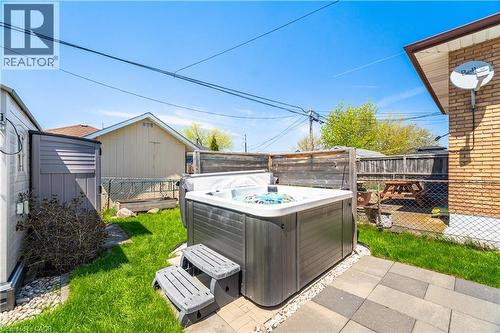 Backyard featuring an outdoor spa with composite steps, paver patio, and a section of manicured lawn - 71 Beland Avenue N, Hamilton, ON 