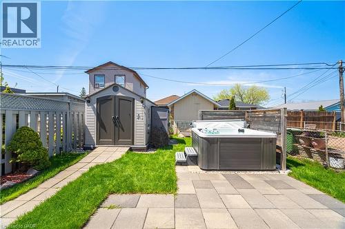 Backyard featuring a paved patio, hot tub, and a storage shed with double doors - 71 Beland Avenue N, Hamilton, ON 