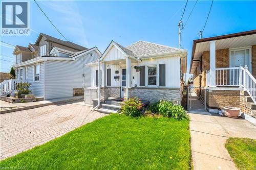 Charming single-story residence with white siding and gray stone veneer accents - 71 Beland Avenue N, Hamilton, ON 