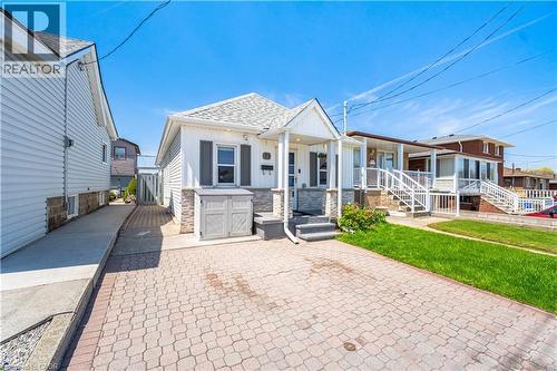 White siding exterior featuring a covered porch entry and stone accents - 71 Beland Avenue N, Hamilton, ON 