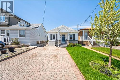 White siding residence featuring a gabled roofline, stone veneer accents, and a covered porch - 71 Beland Avenue N, Hamilton, ON 