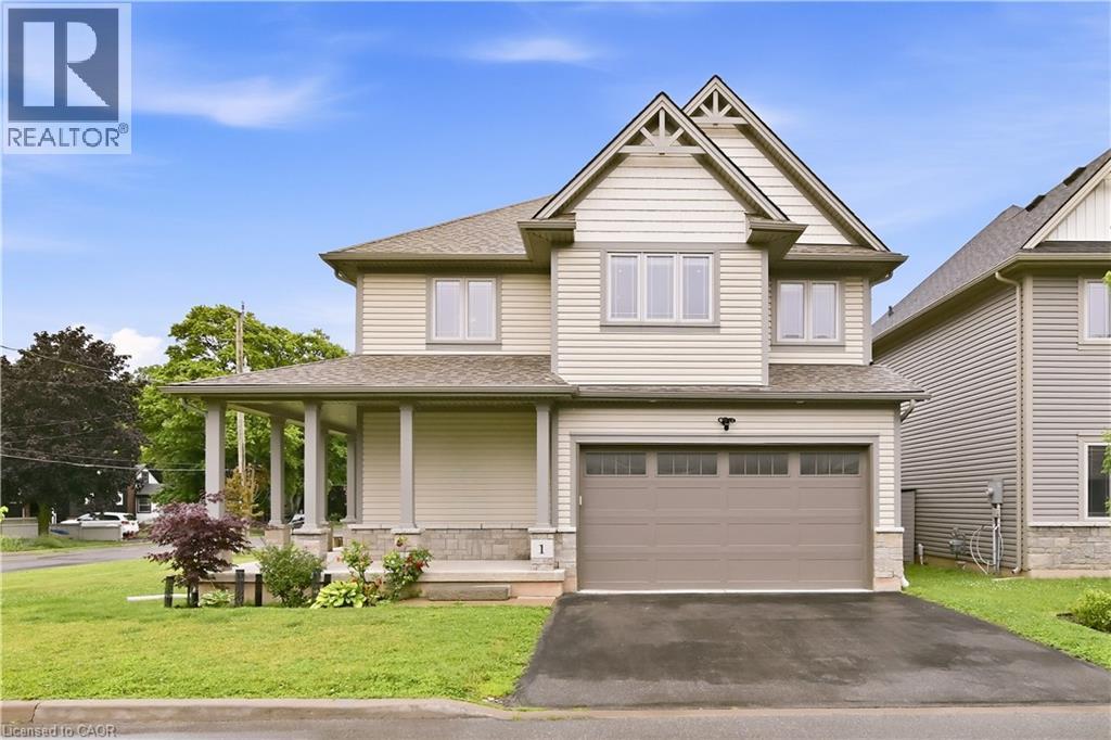 Two-story residence featuring light-toned siding, an integrated garage with a paneled door, and a covered porch with column supports - 1 Lindsay Way, Grimsby, ON - Outdoor