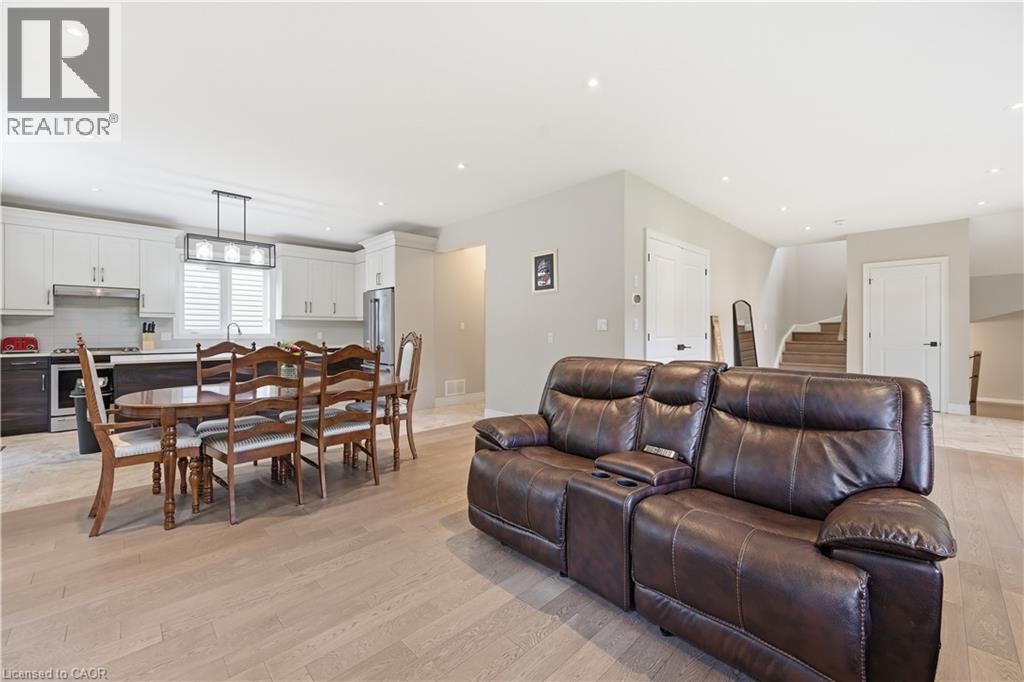 Open-concept living area featuring light wood-finish flooring, recessed lighting, and a contemporary kitchen with white cabinetry, stainless steel appliances, and an island - 1 Lindsay Way, Grimsby, ON - Indoor Photo Showing Living Room