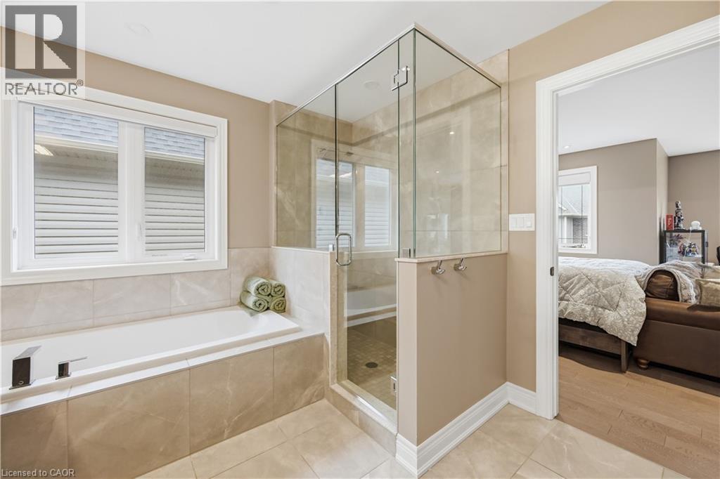 Bathroom featuring a built-in tub with tile surround, a glass-enclosed shower, and neutral wall paint - 1 Lindsay Way, Grimsby, ON - Indoor Photo Showing Bathroom