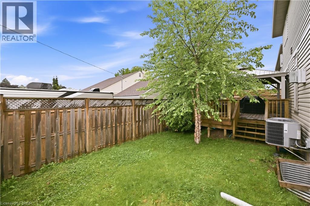 Expansive backyard featuring a manicured lawn, a privacy fence with lattice detailing, and a multi-level wood deck - 1 Lindsay Way, Grimsby, ON - Outdoor
