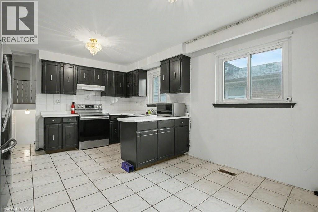 Kitchen featuring dark cabinetry, white countertops, a stainless steel range, and a white tile backsplash - 396 Pinemeadow Avenue, Mississauga, ON