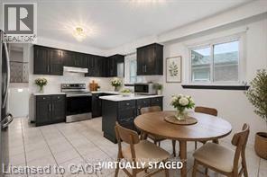 Kitchen featuring dark cabinetry, stainless steel appliances, a white tile backsplash, a center island with countertop, and light-toned floor tiling - 396 Pinemeadow Avenue, Mississauga, ON