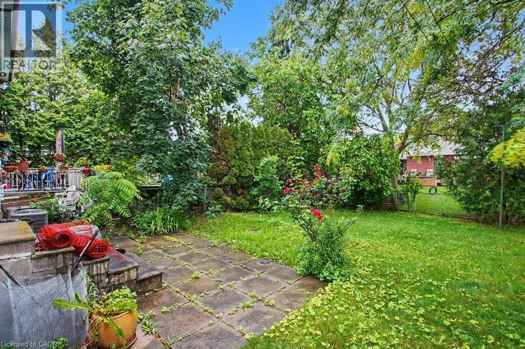 Private backyard featuring mature trees, established plantings, a paved patio, and a grass lawn - 396 Pinemeadow Avenue, Mississauga, ON
