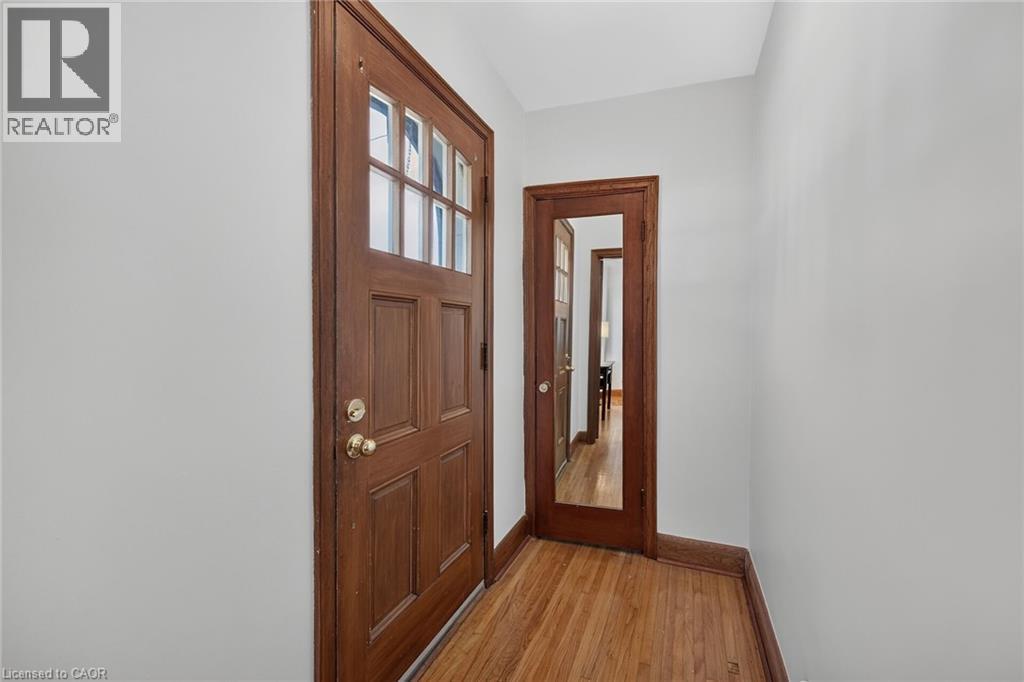 Entryway featuring a wood-panel door with glass inserts, warm wood-finish flooring, and light-toned walls - 83 Aberfoyle Avenue, Hamilton, ON