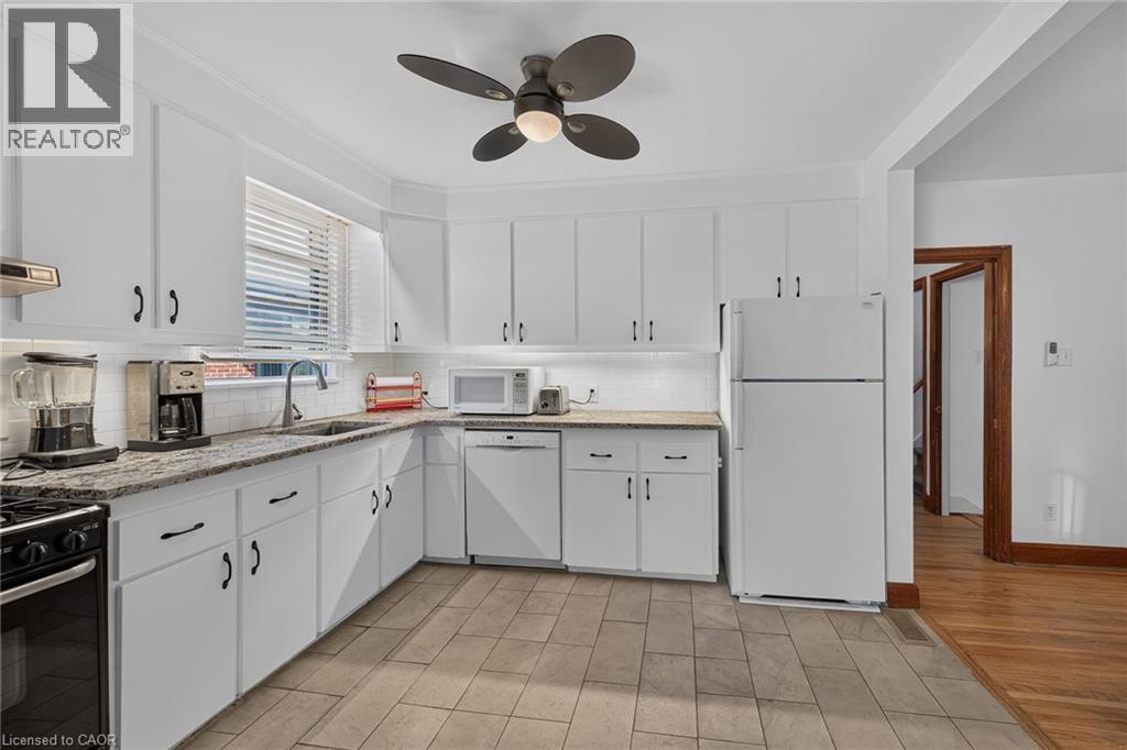 Kitchen featuring white cabinetry, light-toned countertops, tile flooring, and a ceiling fan - 83 Aberfoyle Avenue, Hamilton, ON