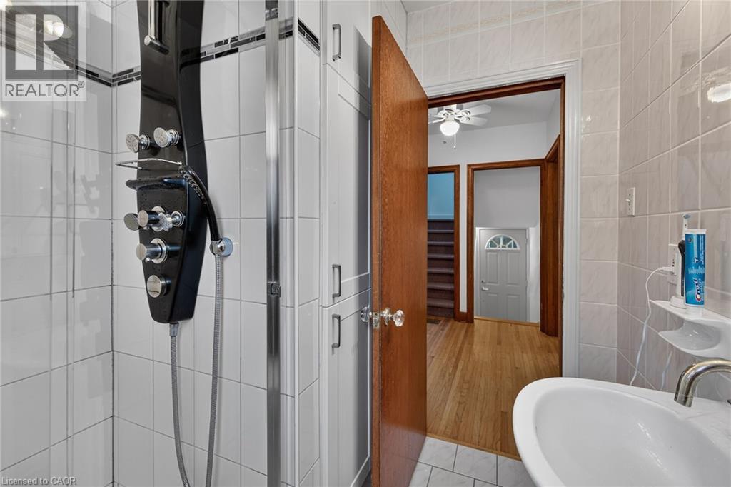 Shower enclosure featuring a multi-function shower panel with multiple spray options and a handheld shower - 83 Aberfoyle Avenue, Hamilton, ON