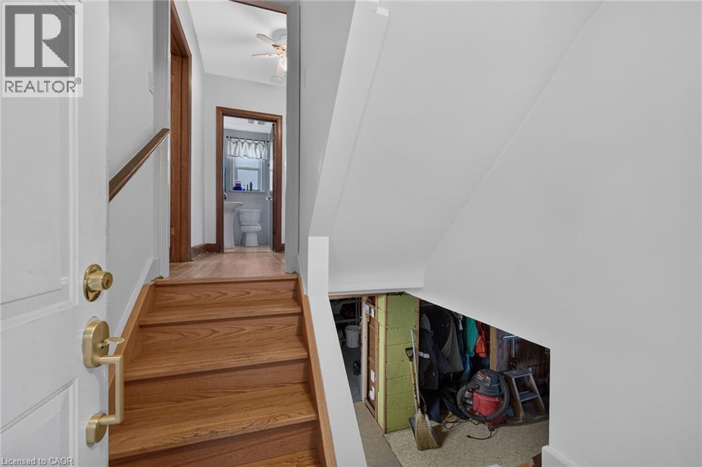 Hardwood stairs with brass handrail leading to a landing with wood-finish flooring - 83 Aberfoyle Avenue, Hamilton, ON