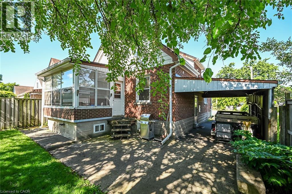 Exterior showcasing a brick facade, an enclosed sunroom with large windows, and a covered carport - 83 Aberfoyle Avenue, Hamilton, ON
