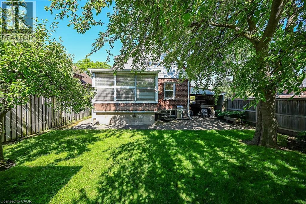Expansive backyard featuring a lush lawn, mature shade trees, and a privacy fence - 83 Aberfoyle Avenue, Hamilton, ON