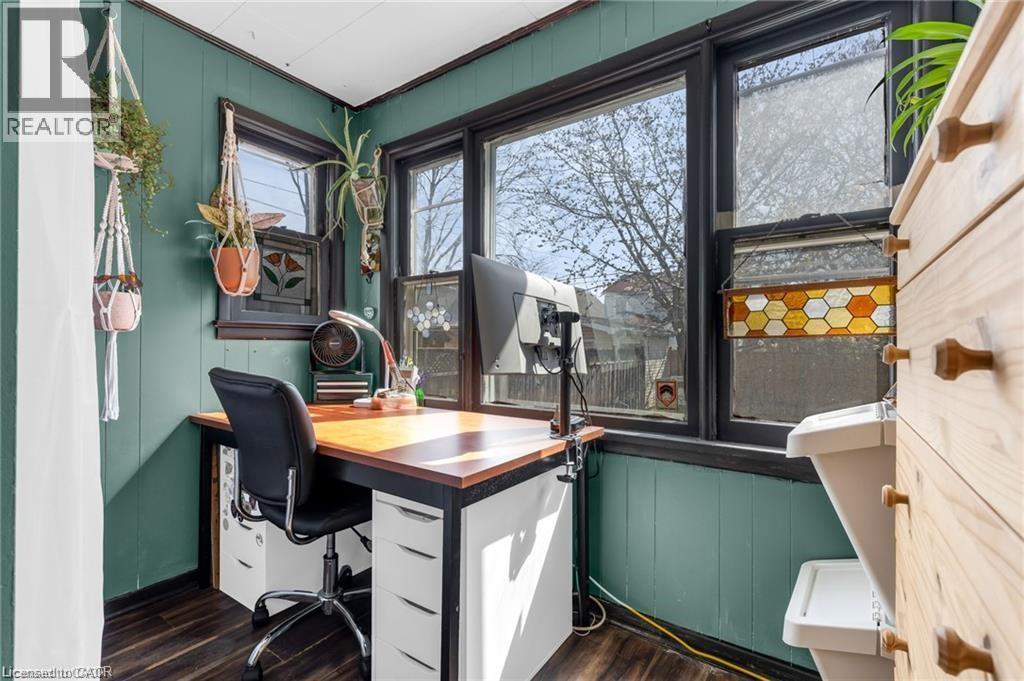 Bright room featuring dark-framed windows, a decorative stained-glass panel, and a wood-finish floor - 22 Cope Street, Hamilton, ON