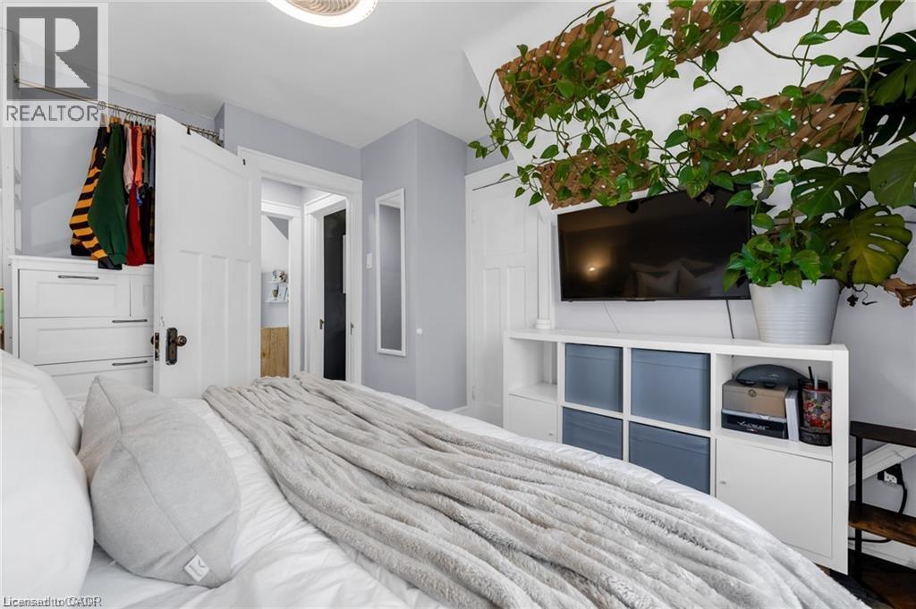 Bedroom featuring light gray walls, white trim, and a built-in closet system with drawers and hanging space - 22 Cope Street, Hamilton, ON