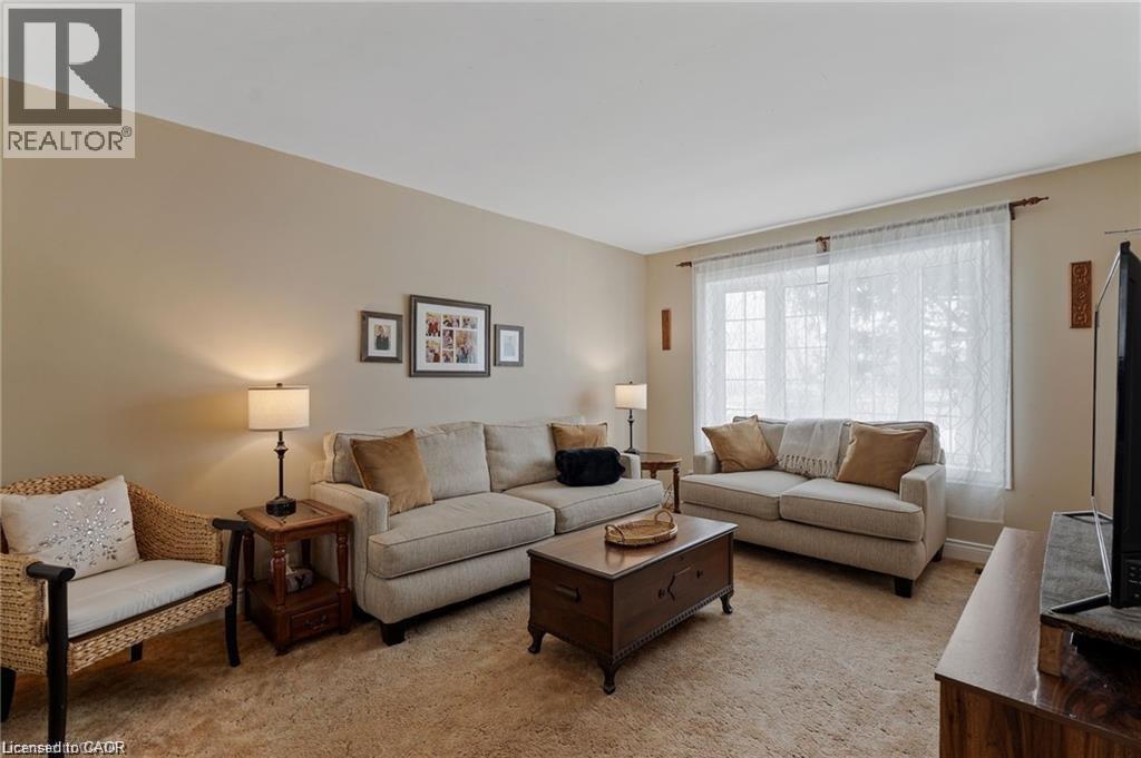 Spacious living area featuring neutral-toned walls, soft carpet flooring, and a large window with ample natural light - 2 Mill Street E, York, ON