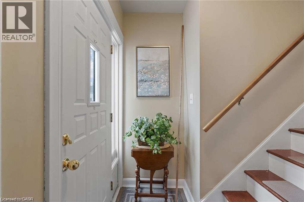 Entryway featuring a paneled door with a rectangular window, brass hardware, and a wood-finish staircase with a natural wood handrail - 2 Mill Street E, York, ON