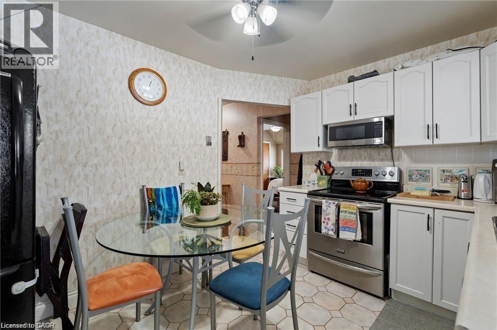 Kitchen area featuring white cabinetry, stainless steel appliances, and hexagonal floor tiling - 2 Mill Street E, York, ON