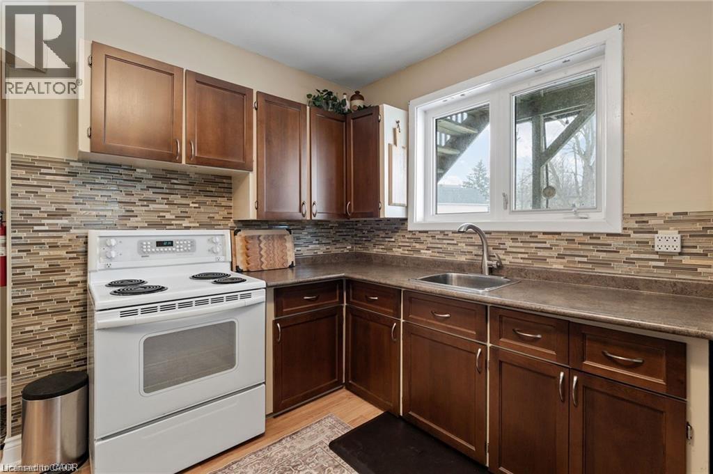 Kitchen featuring wood-finish cabinetry, a white electric range, and a mosaic tile backsplash - 2 Mill Street E, York, ON