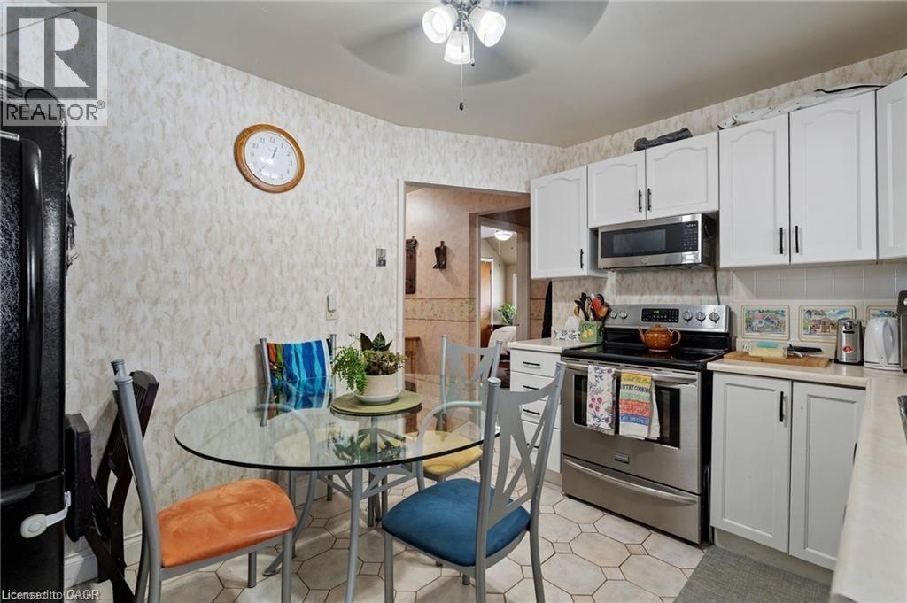 Kitchen featuring white cabinetry with dark hardware, stainless steel appliances, and a built-in microwave - 2 Mill Street E, York, ON