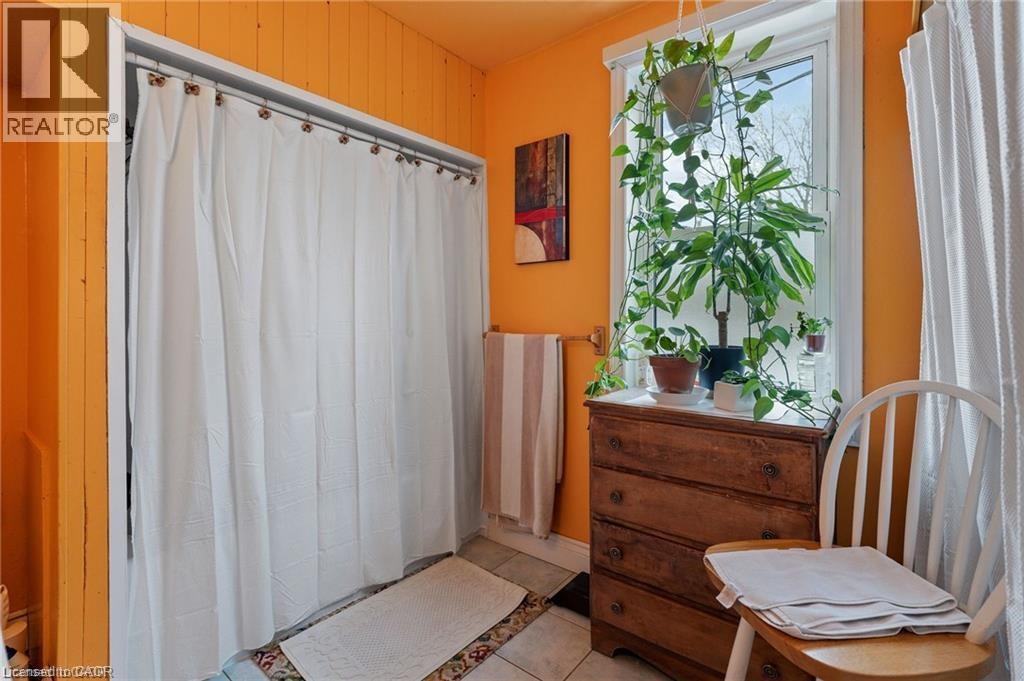Tiled flooring with a white shower curtain enclosure and bright orange paneled walls - 2 Mill Street E, York, ON