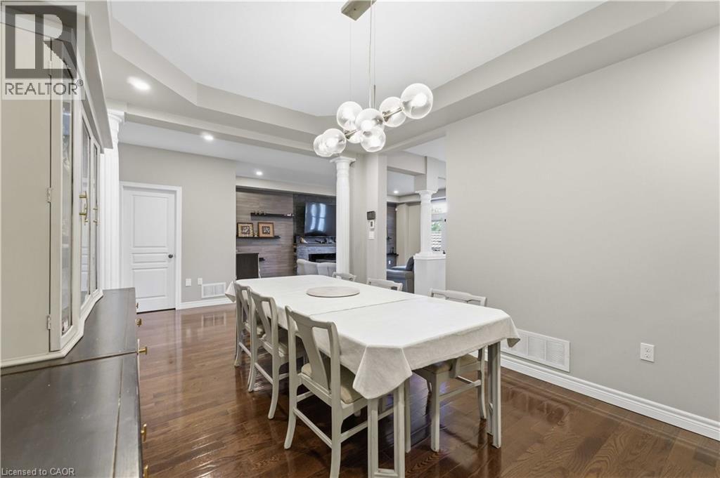 Open-concept dining area featuring wood-finish flooring, a contemporary chandelier, recessed lighting, and tray ceiling detailing - 212 Chartwell Circle, Hamilton, ON