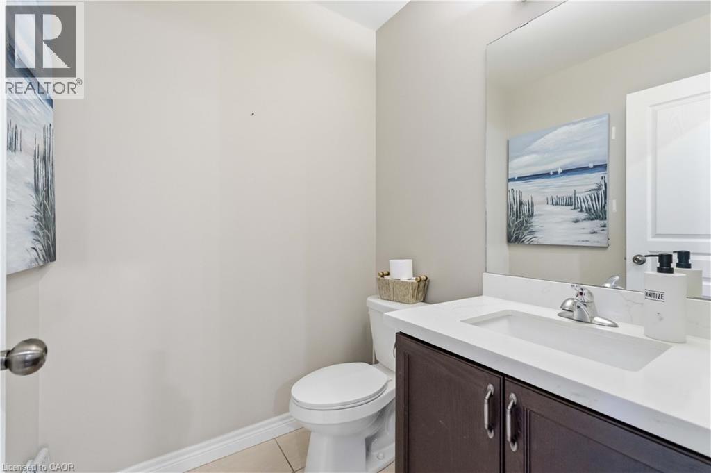 Bathroom featuring a dark wood-finish vanity with a white countertop, an integrated sink, and a chrome faucet - 212 Chartwell Circle, Hamilton, ON