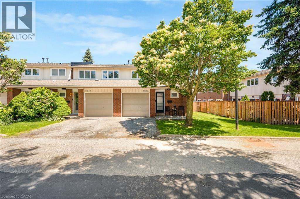 Townhome exterior with brick accents, tan siding, and a gabled roofline - 5275 Banting Court, Burlington, ON