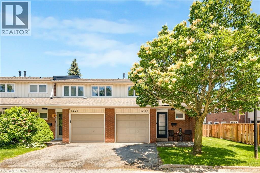 Brick and siding townhome featuring an attached single-car garage, mature front yard tree, and front entry porch with an exterior light fixture - 5275 Banting Court, Burlington, ON